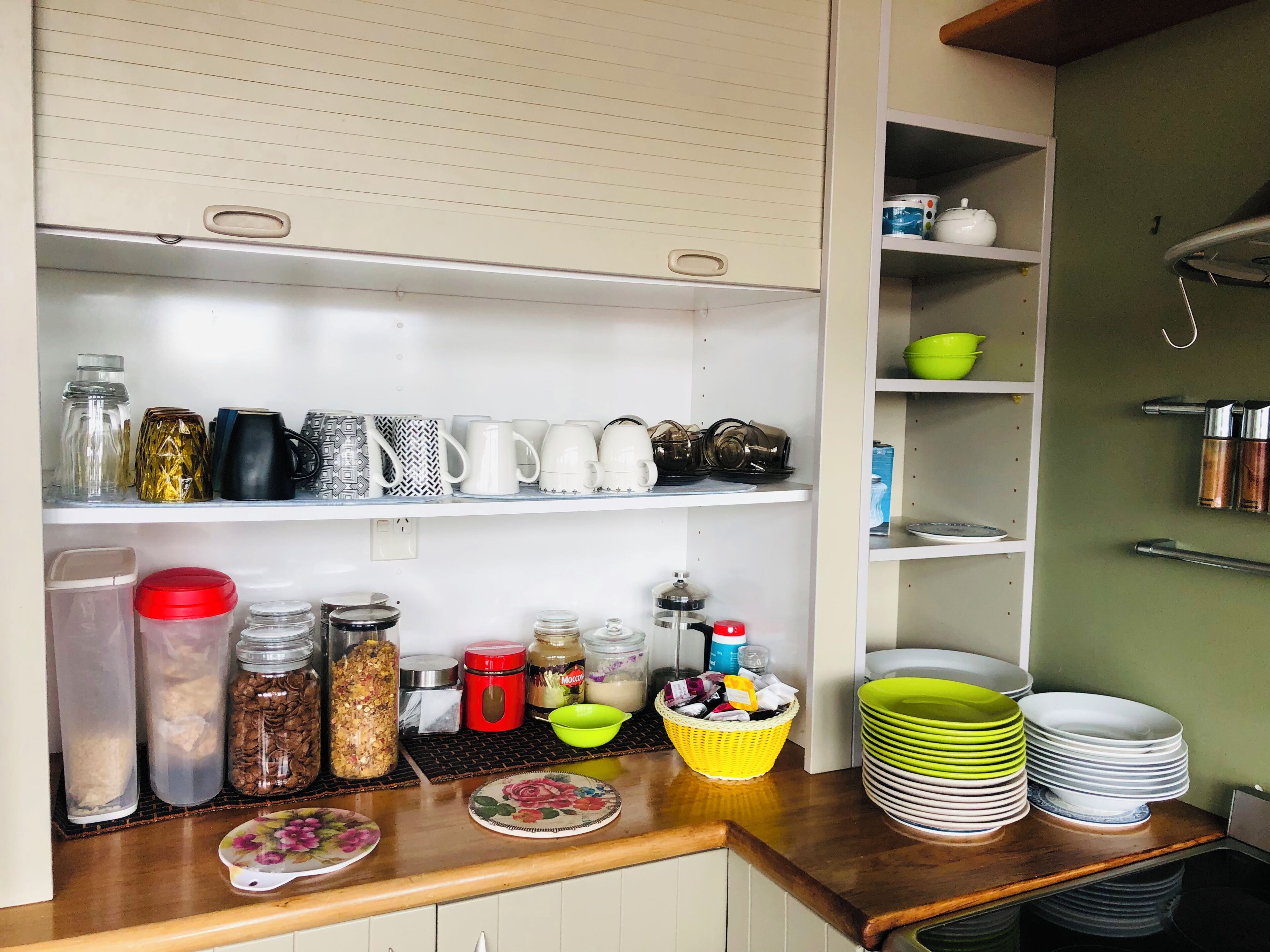 Una cocina con estantes que contienen frascos, tazas y platos.