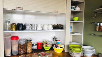 Una cocina con estantes que contienen frascos, tazas y platos.