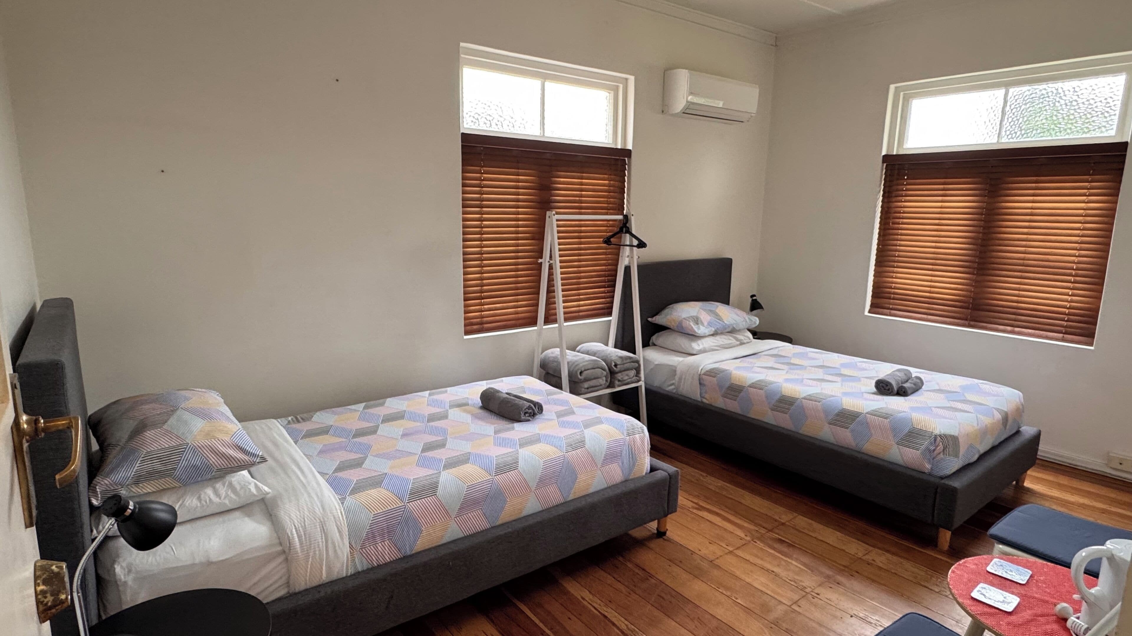 Una habitación con dos camas individuales, una mesita y una silla.