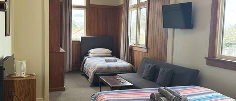 Una habitación de hotel con una cama grande, un sofá, un escritorio y un televisor.