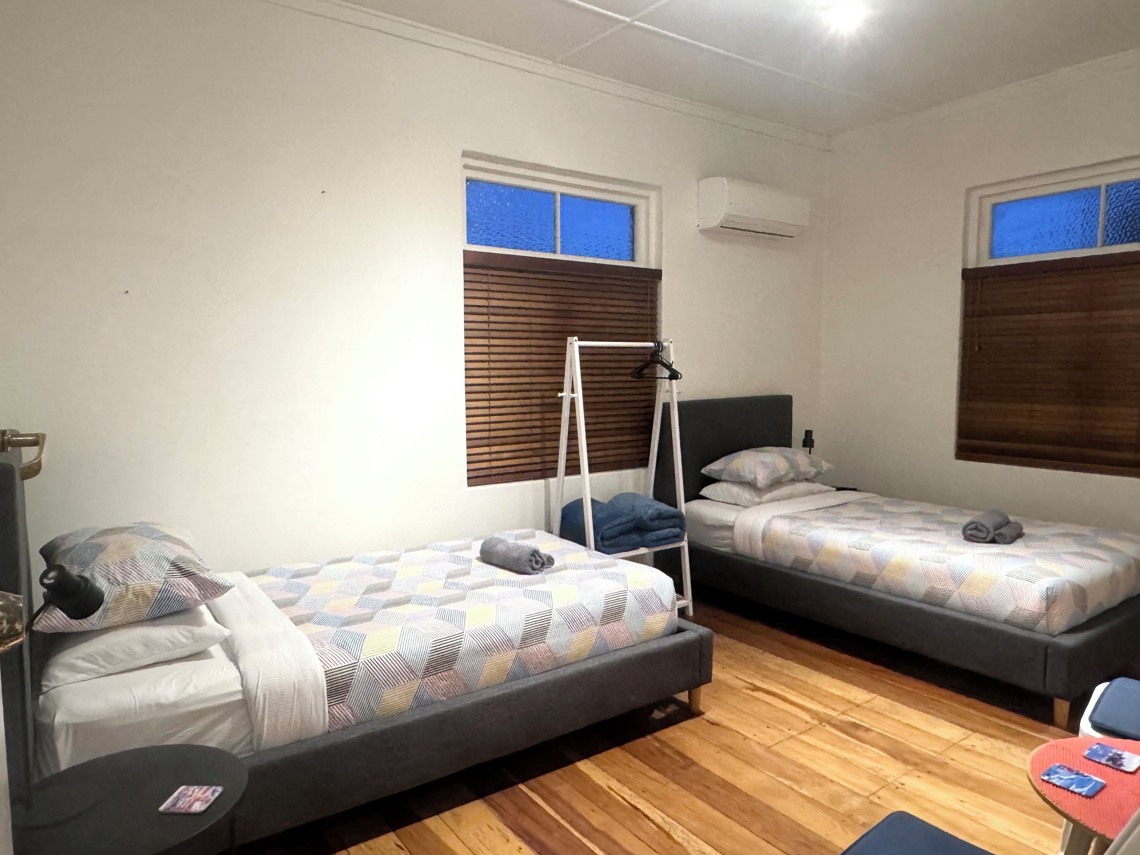A room with two single beds, a small table, and a chair.