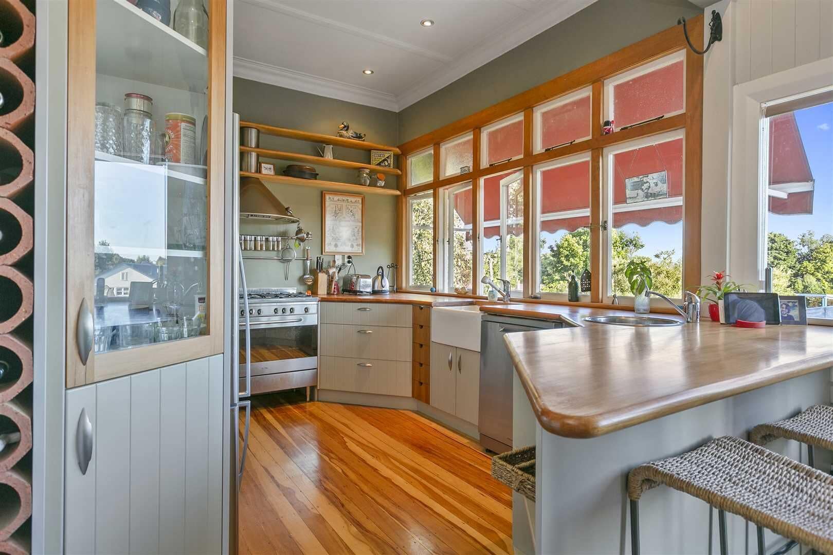 Cocina con horno empotrado, un lavamanos y una ventana con vistas a la vegetación.