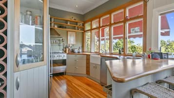 A kitchen with a built-in oven, a sink, and a window with a view of greenery.