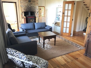 A living room with a sectional sofa, a coffee table, a fireplace, and a bookshelf.