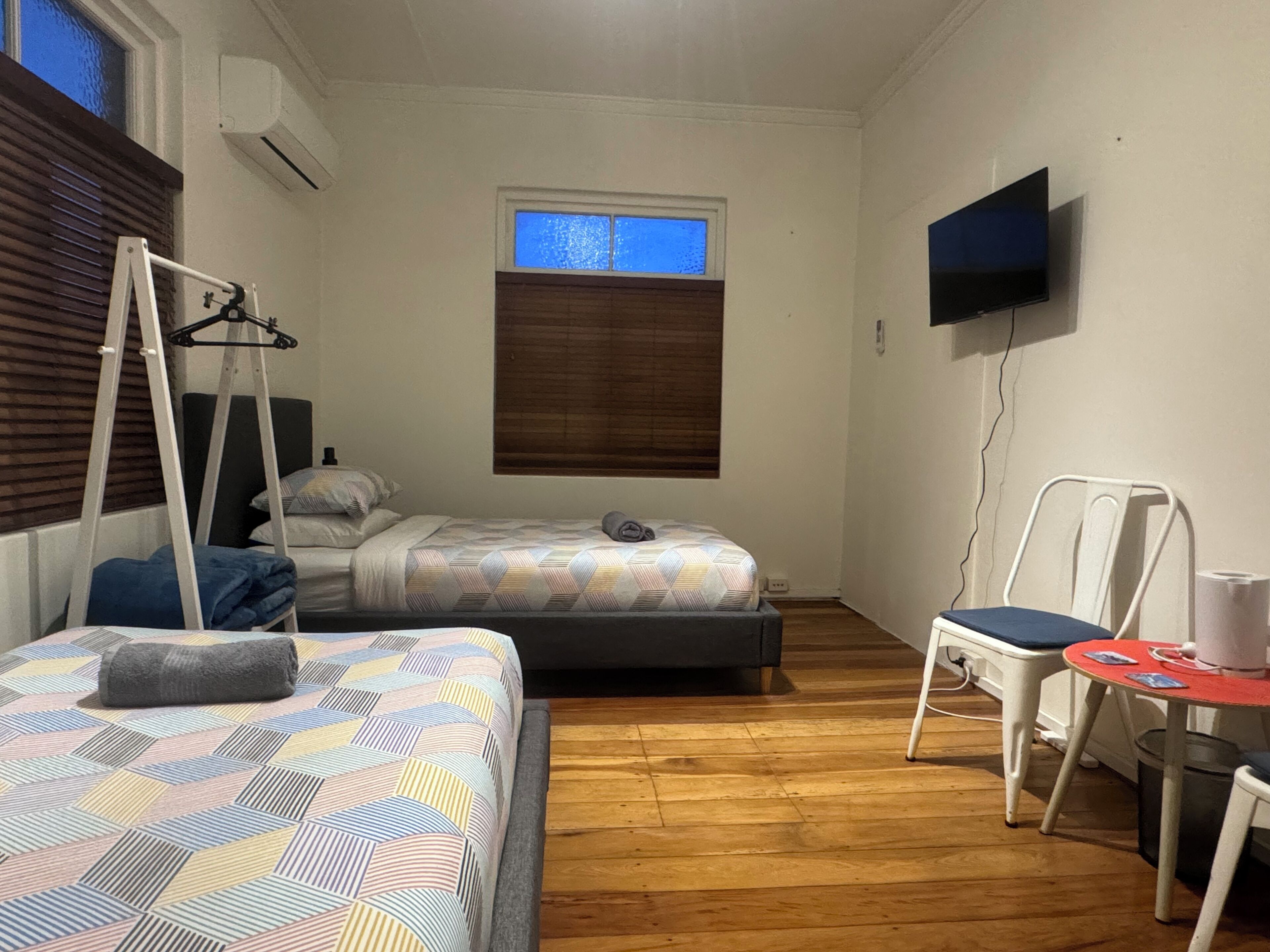 A room with two beds, a TV, a chair, and a small table.