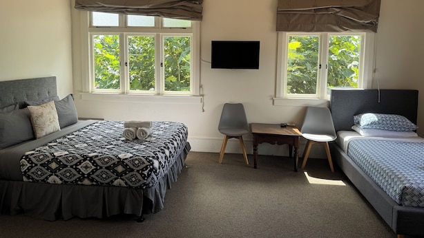 A bedroom with two beds, a desk, and a TV. - Penmarric House - Self Check-in (Cambridge)