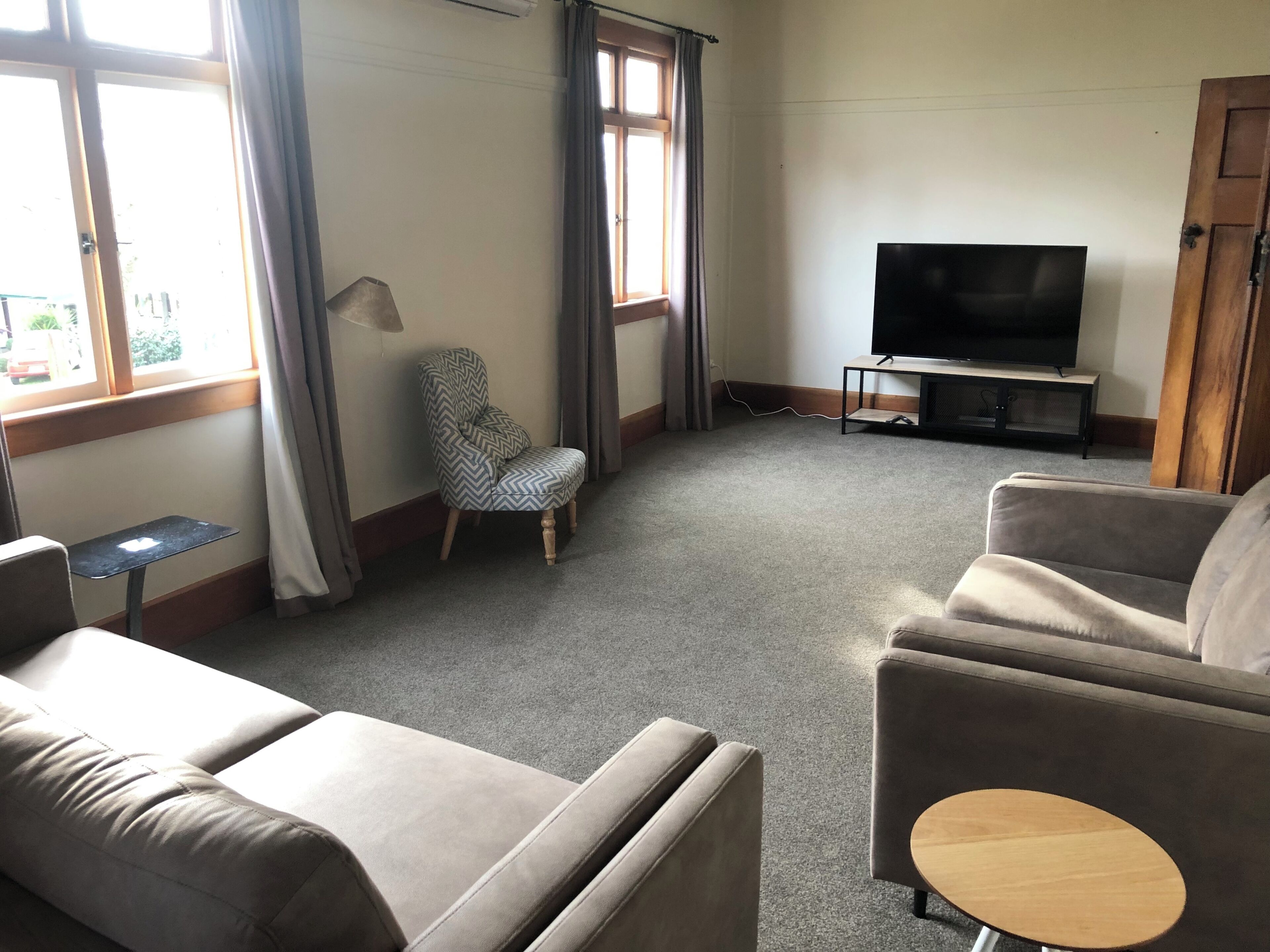 Una sala de estar con un sofá, un sillón y un televisor sobre un mueble.