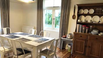 A dining area with a table set for four, a window with curtains, and a wooden cabinet with dishes.