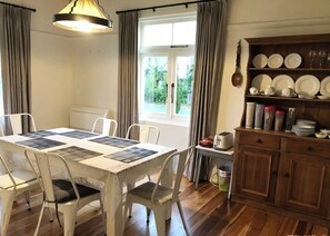 A dining area with a table set for four, a window with curtains, and a wooden cabinet with dishes.