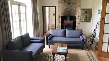 A living room with a fireplace, two sofas, a coffee table, and a patterned rug.