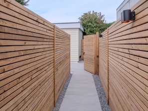 A narrow pathway flanked by wooden fences leading to a building. - Cozy Bungalow Retreat in Edinburgh (Edinburgh)