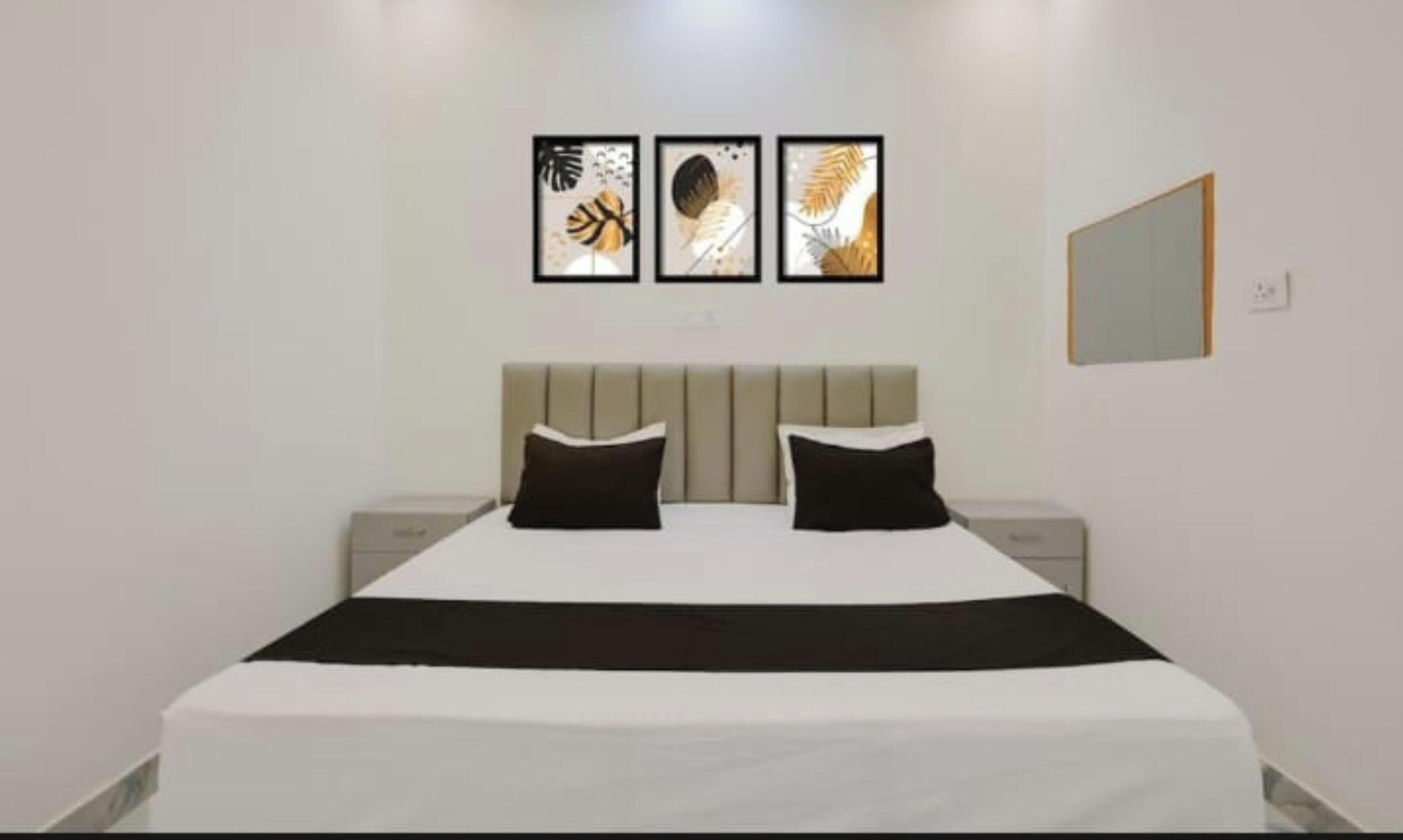 Ein Schlafzimmer mit einem Bett, zwei Nachttischen und drei gerahmten Kunstwerken an der Wand.