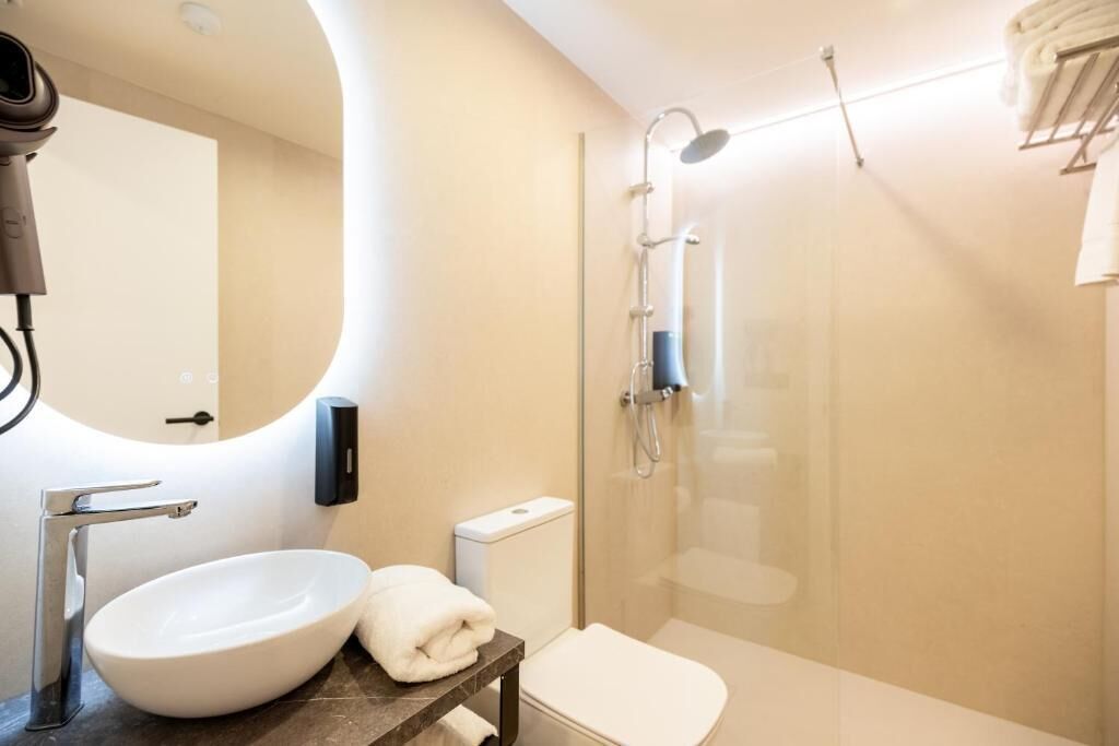 A modern bathroom with a sink, toilet, and shower.