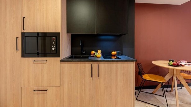 Una cocina compacta con microondas, pileta y comedor con mesa y sillas.