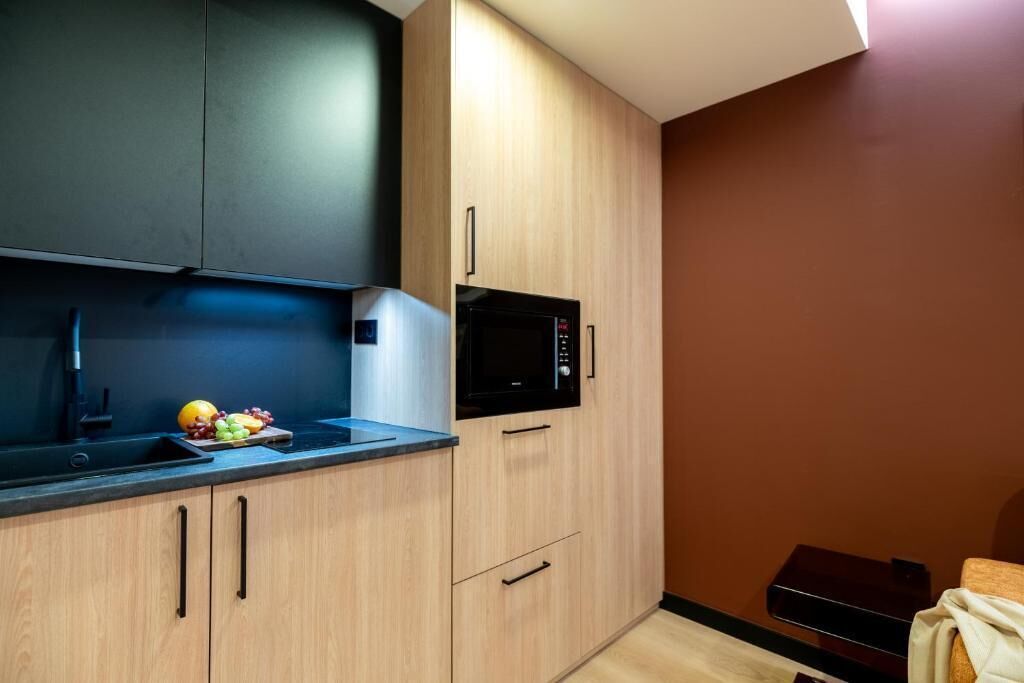 Une cuisine compacte équipée d’un four à micro-ondes, d’un évier et d’un panier à fruits posé sur le plan de travail.