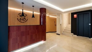 Un moderno vestíbulo de hotel con una recepción, una escalera y una puerta.