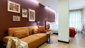 Una habitación de hotel moderna con un sofá, una pequeña mesa redonda y obras de arte en las paredes.
