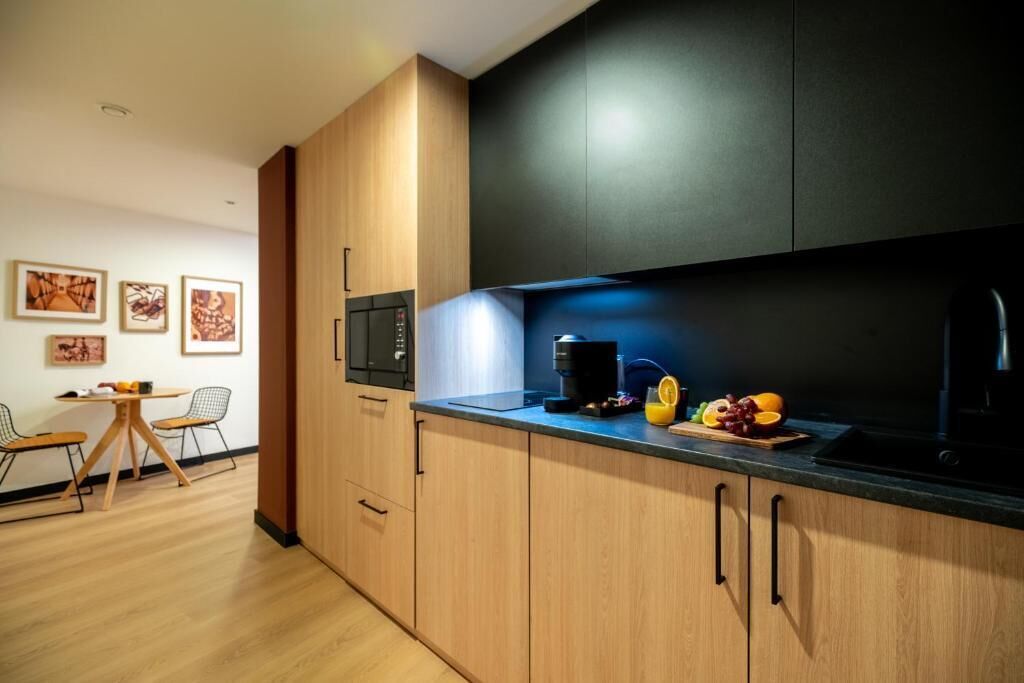 Una cocina moderna con armarios de madera, encimera negra y un comedor con mesa y sillas.