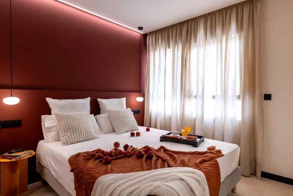 A modern hotel room with a large bed, a bedside table, and a window with curtains.