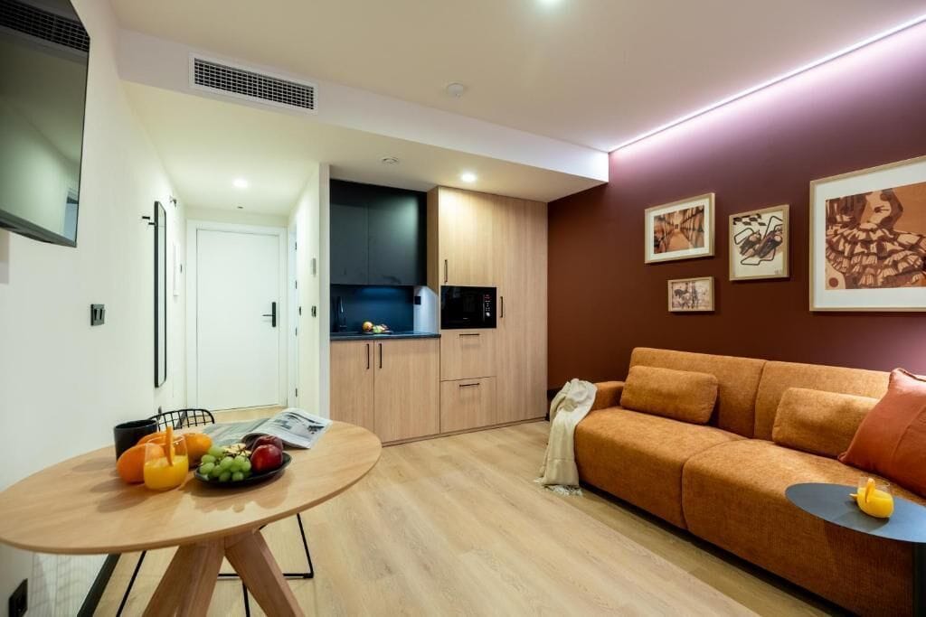 Un espacio moderno de estar con comedor, kitchenette y sofá.