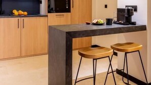 Una cocina moderna con armarios de madera, una encimera negra y dos taburetes de bar.