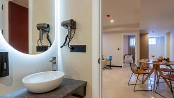 Un bany modern amb un mirall gran, un lavabo blanc i dos assecadors de cabell penjats a la paret.