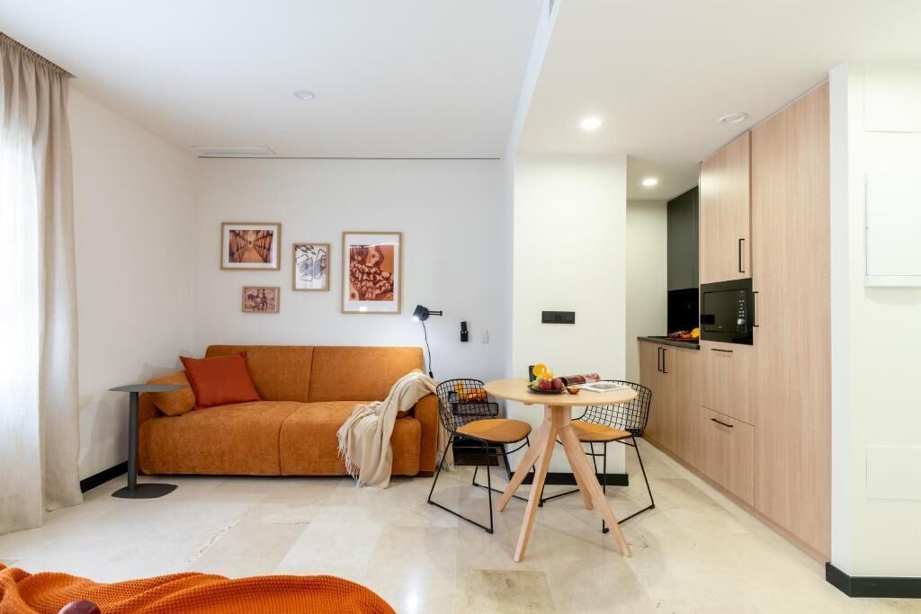 Een moderne woonkamer met een bank, een eettafel en een keuken met kasten en apparatuur.