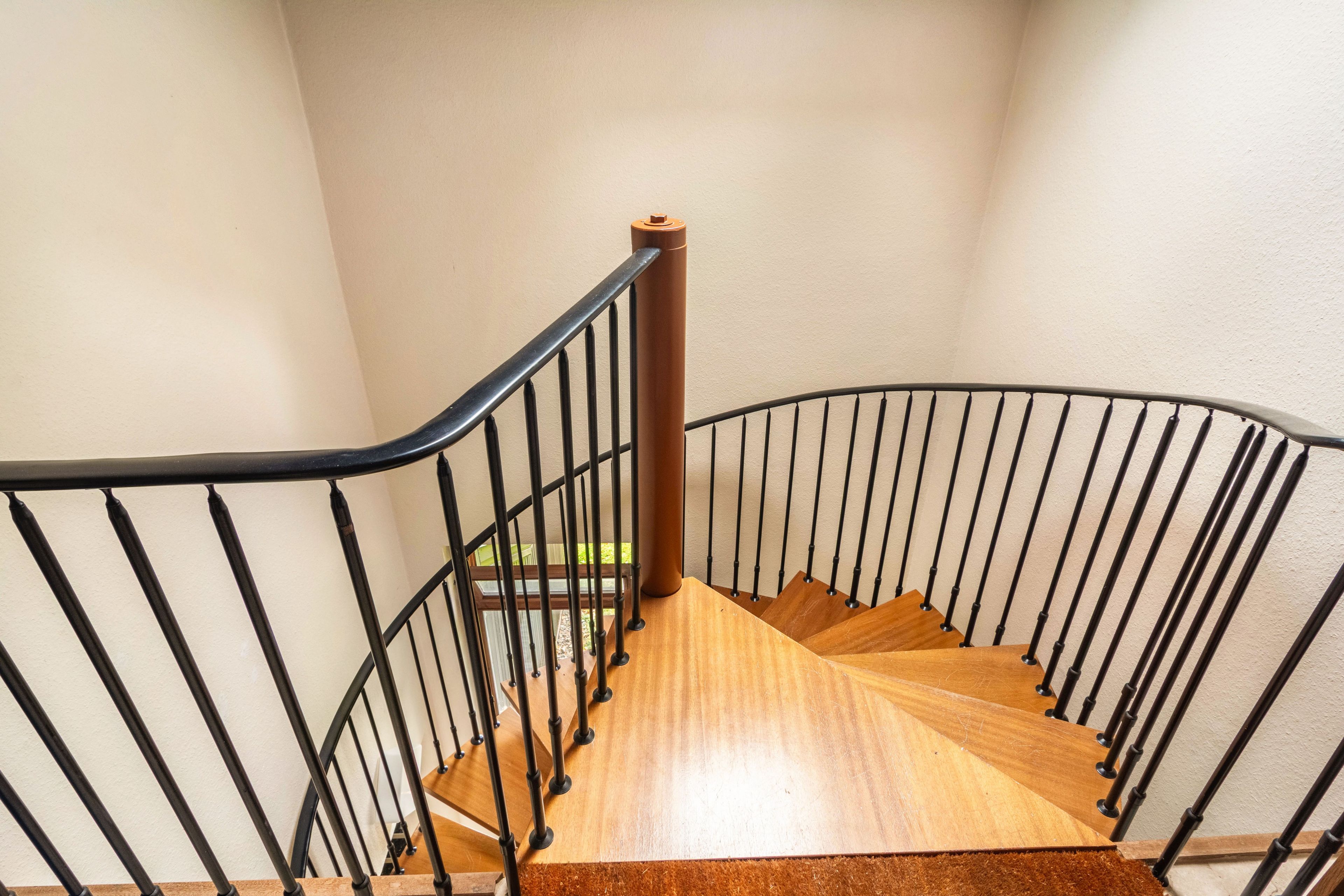 A wooden staircase with black metal railings leading to an upper floor.