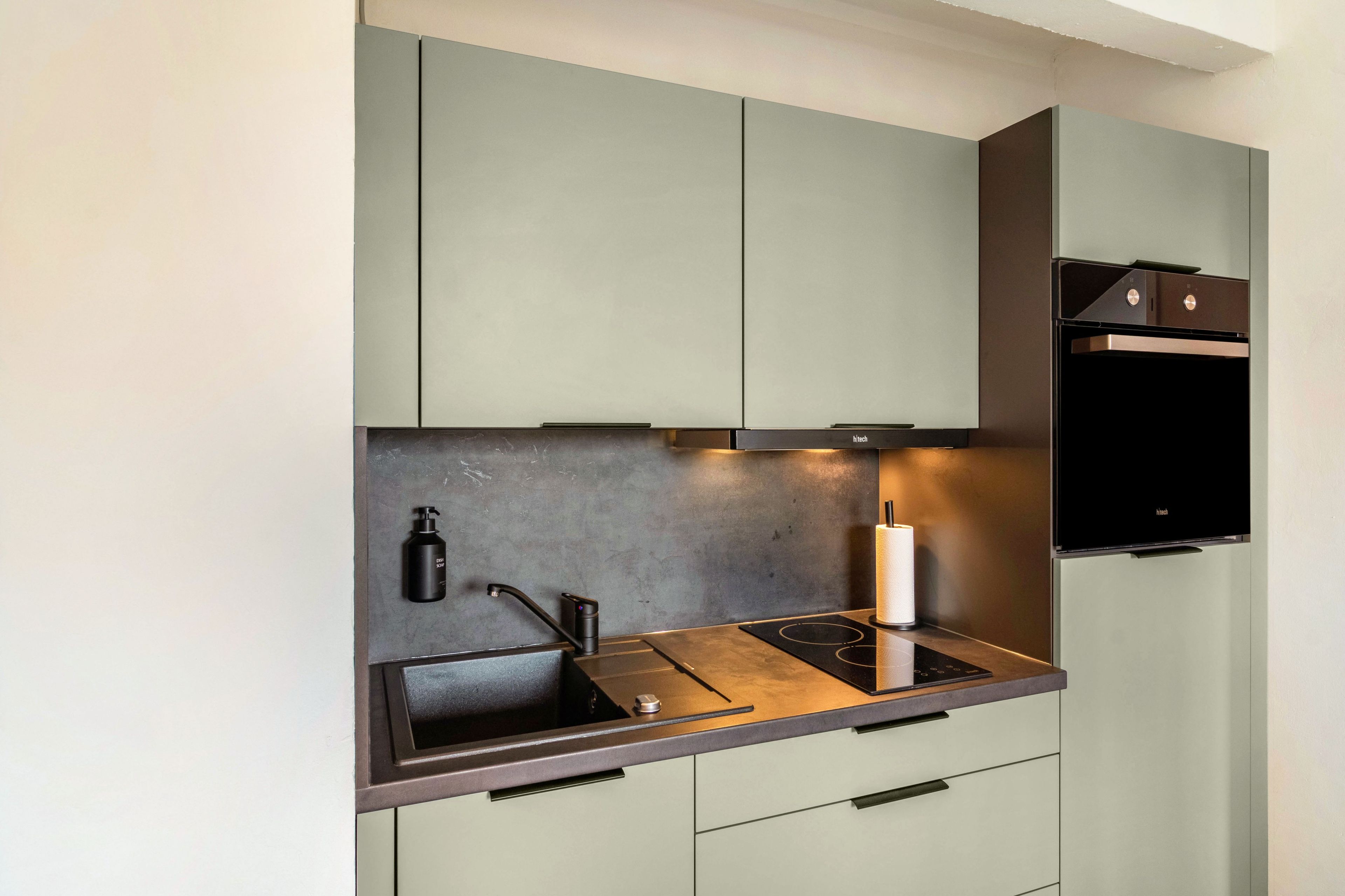 A modern kitchen with a built-in stove, a sink, and a compact refrigerator.