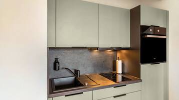 A modern kitchen with a built-in stove, a sink, and a compact refrigerator.