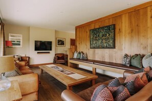 Ein gemütliches Wohnzimmer mit einer hölzernen Bank, Ledersofas und einem Fernseher.