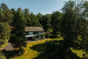 Ein zweistöckiges Haus mit überdachter Terrasse und Rasen davor.