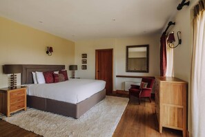 Een slaapkamer met een groot bed, nachtkastjes, een stoel, een bureau en een kledingkast.