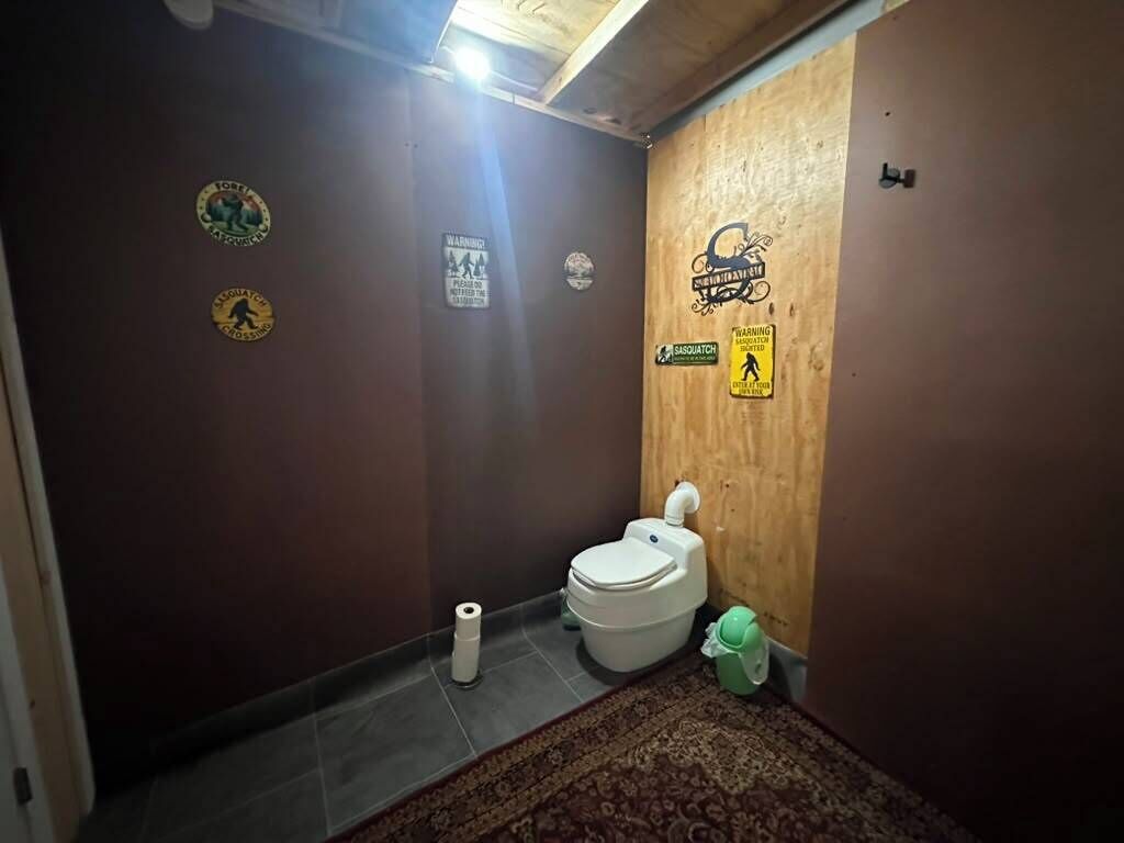 Une petite salle de bain avec des toilettes, un tapis et divers autocollants sur le mur.