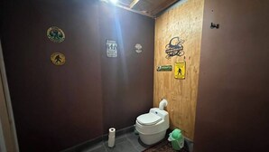 A small bathroom with a toilet, a rug, and various stickers on the wall.