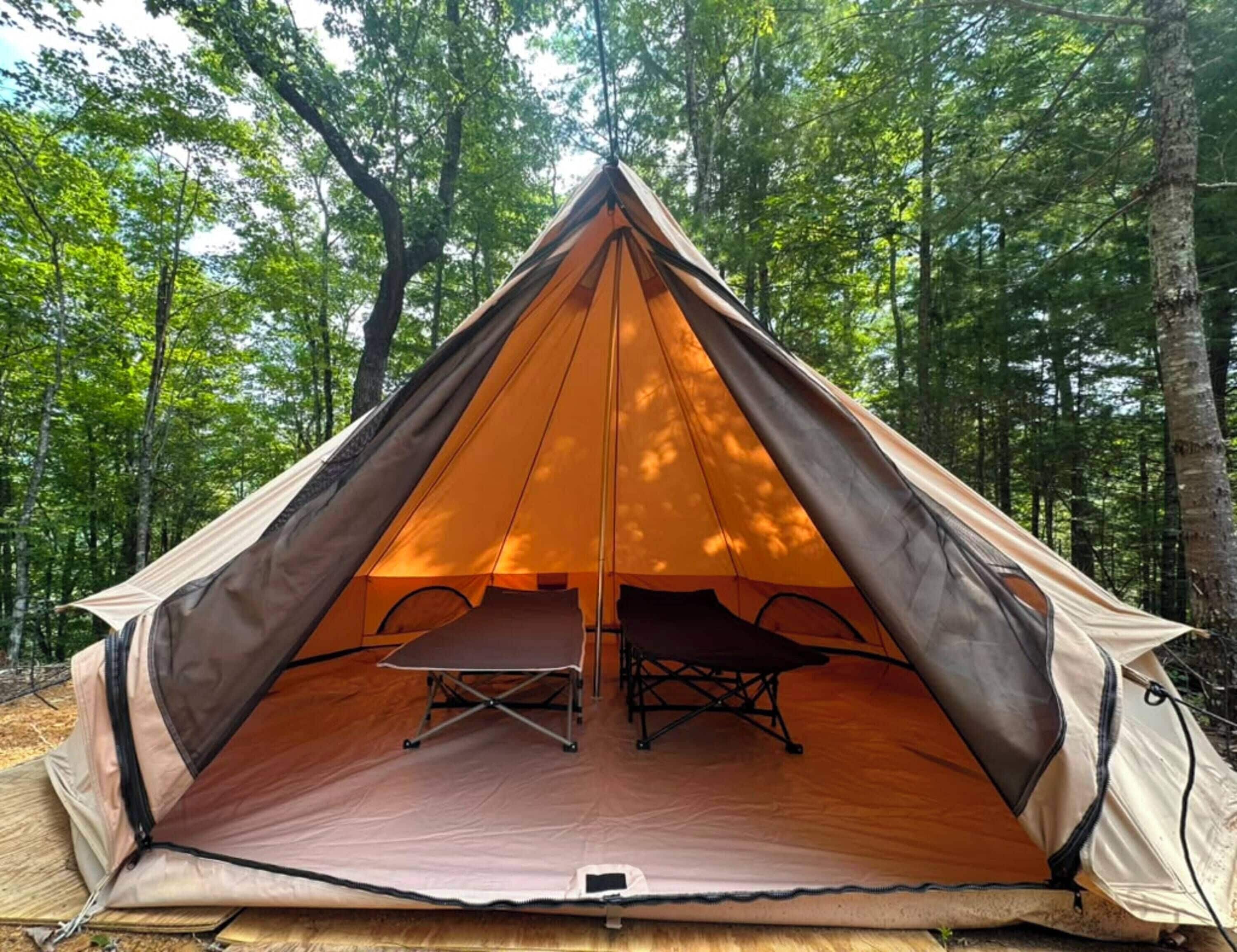 A dome-shaped tent with an open interior, a foldable table, and a bench.