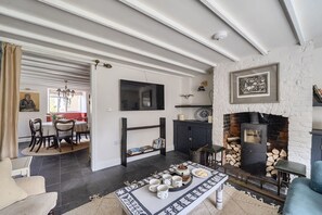 Ein Wohnzimmer mit Kamin, einer Essecke mit einer Chandelierleuchtre und einem an der Wand montierten Fernseher.