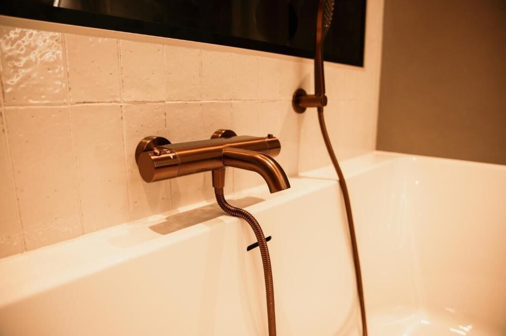 Een bad met douchekop en douche slang.