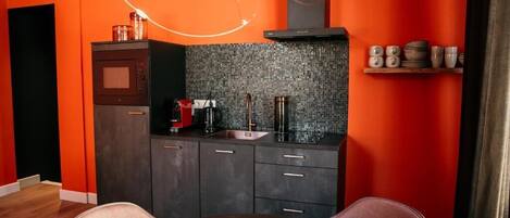 A compact kitchen with a microwave, coffee maker, and a sink.