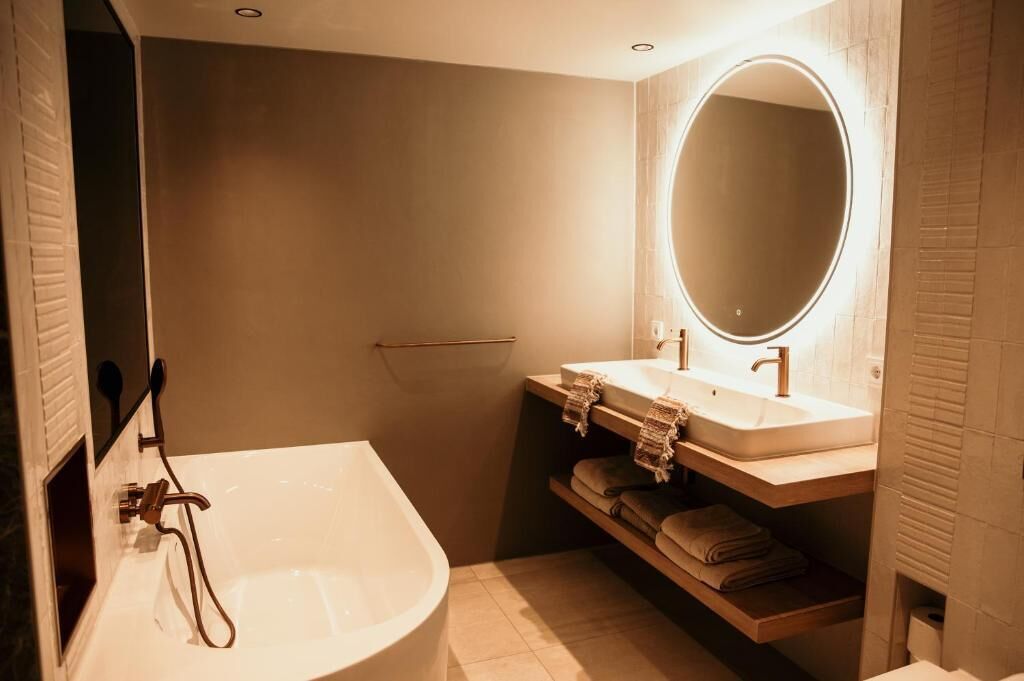 Un baño moderno con una bañera independiente, un tocador con espejo y un perchero para toallas.