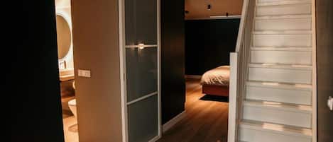 A bedroom with a bed, a sliding door, and a staircase.
