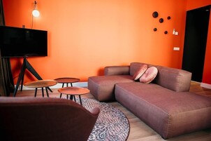 Una sala de estar moderna con un sofá seccional, un televisor de pantalla plana y una mesa de centro.