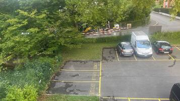 A parking area with marked spaces, a white van, and a silver car.