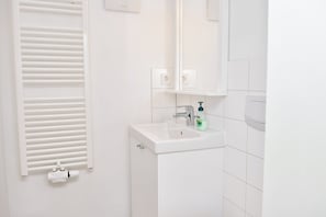 A bathroom with a white sink, a mirror, a towel rack, and a toilet paper holder. - Townhouse Duderstadt: Studio 2 (Duderstadt)