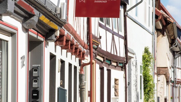 Ein traditionelles europäisches Gebäude mit einem roten Schild, das auf ein Stadthaus hinweist.
