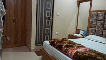 A bedroom with a bed, a wardrobe, a mirror, and a nightstand.