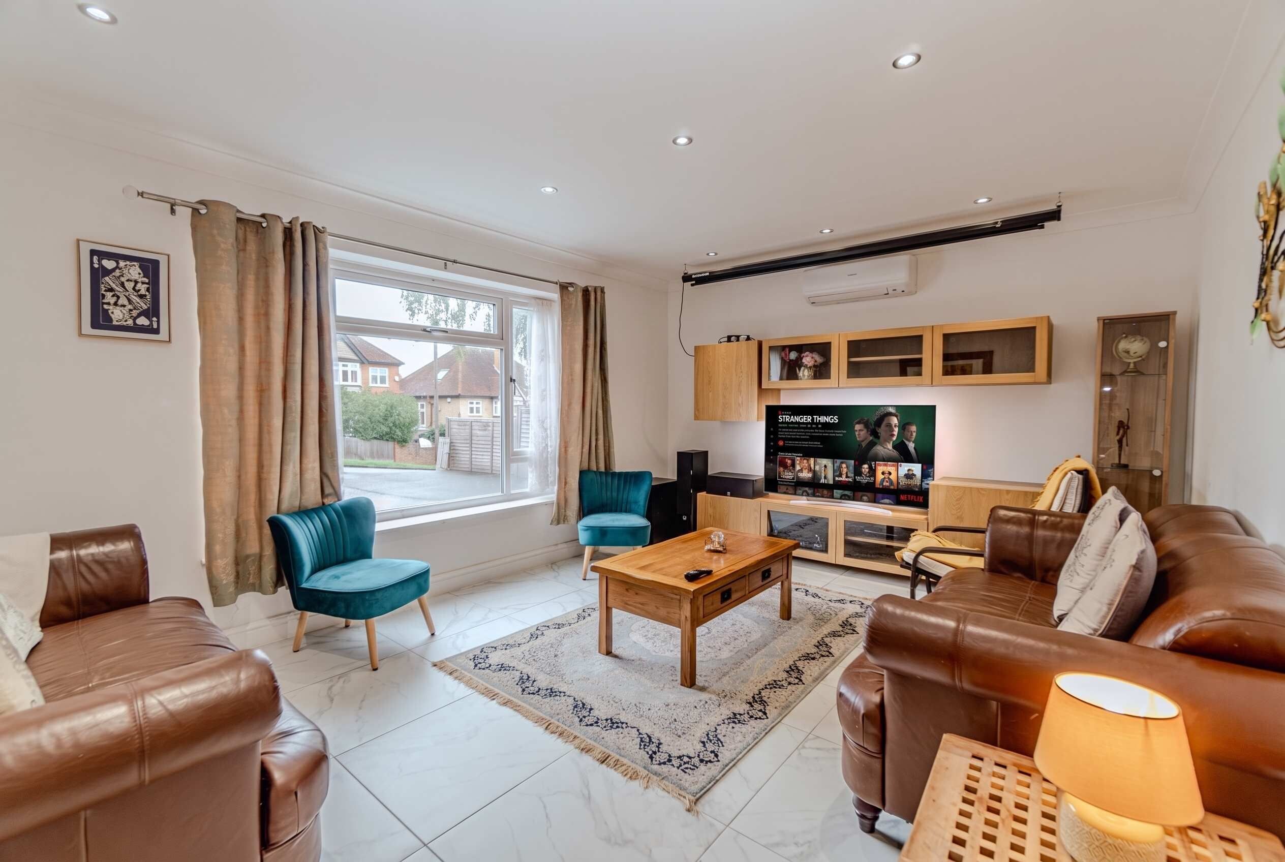 A modern living room with leather sofas, a coffee table, a TV, and a view of the outside.