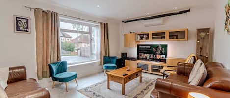 A modern living room with leather sofas, a coffee table, a TV, and a view of the outside.