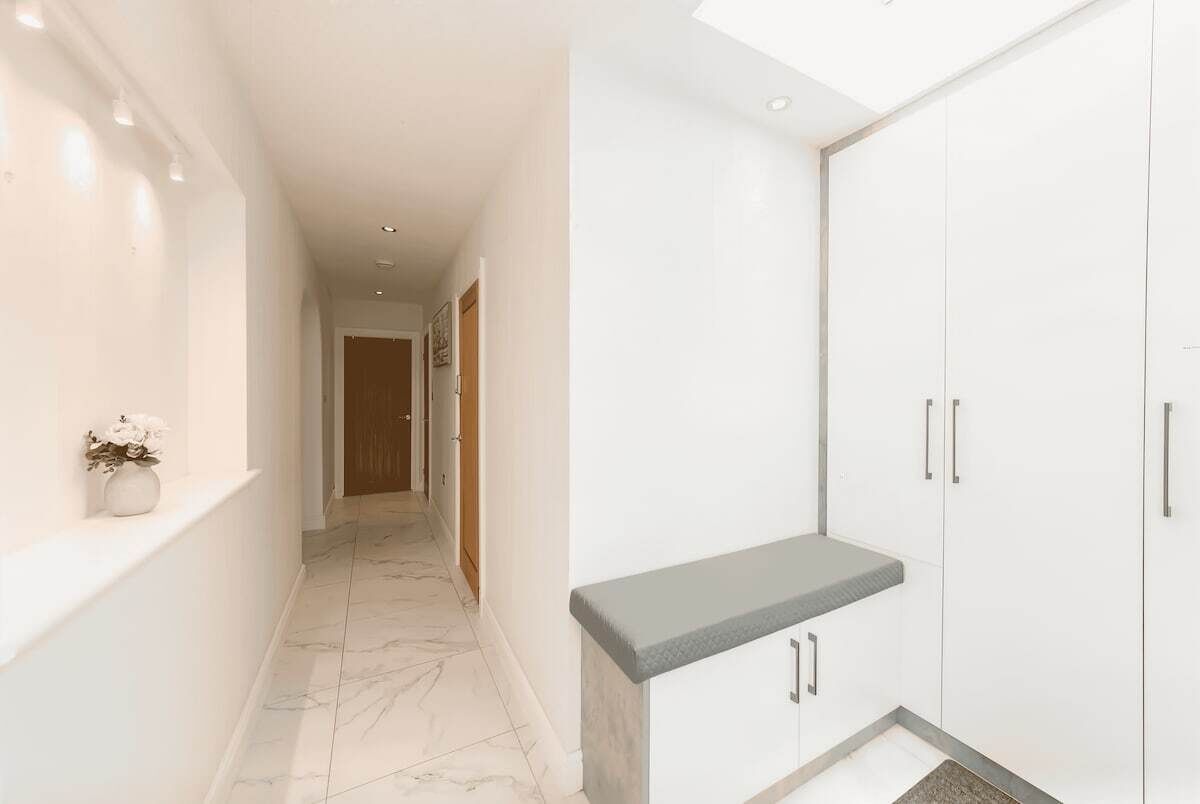 A hallway with a marble floor, white walls, and a bench with a grey top.