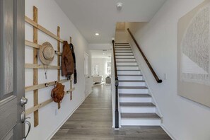 A hallway with a wooden wall-mounted rack, a staircase with a wooden handrail, and a white door. - Tranquil 3-bedroom townhome with AC in vibrant Atlanta (Atlanta)